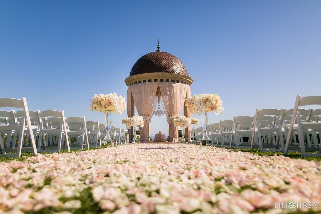 Outdoor wedding ceremony aisle with white chairs and floral arrangements