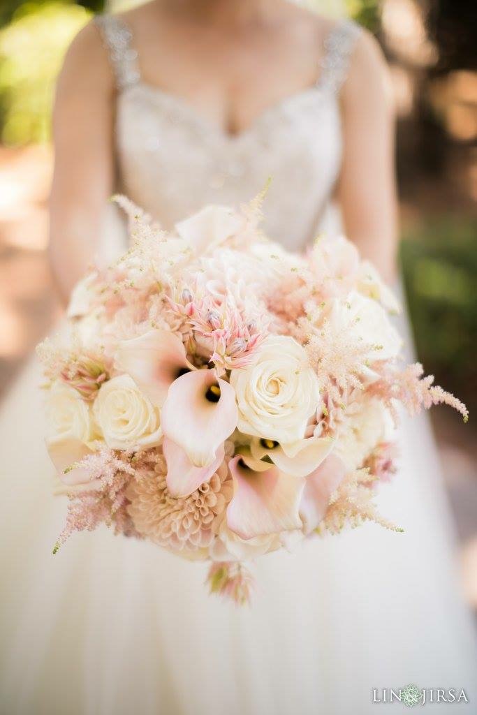 Soft blush bridal bouquet held against a wedding dress